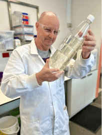 A person in a white coat holding a bottle of liquid

AI-generated content may be incorrect.